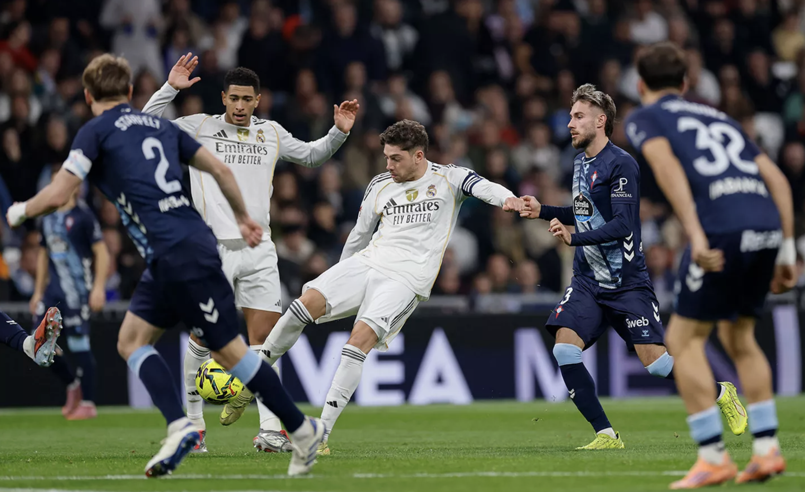 Jugador de Futbol rematando un balon rodeado de 3 defensores del equipo rival